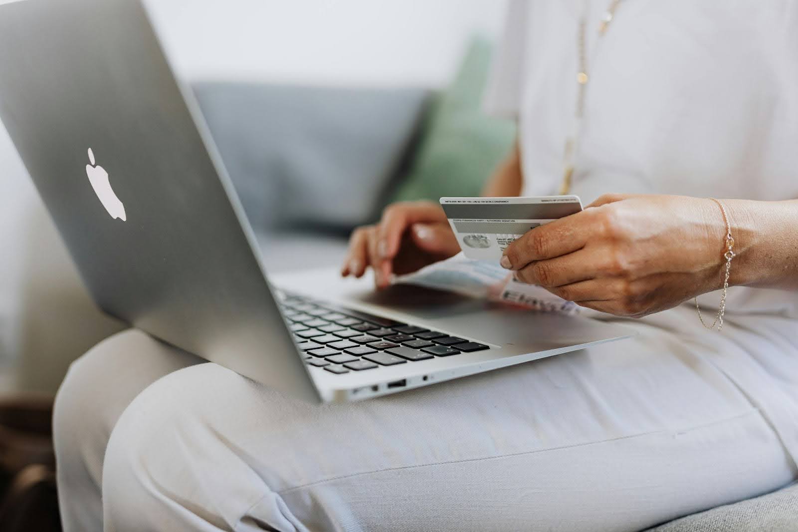 Person holding a credit card while using a laptop